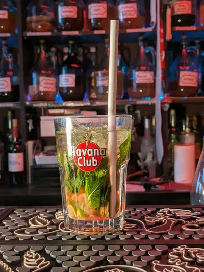 Verre cocktail au comptoir, bonbonnes en arrière-plan