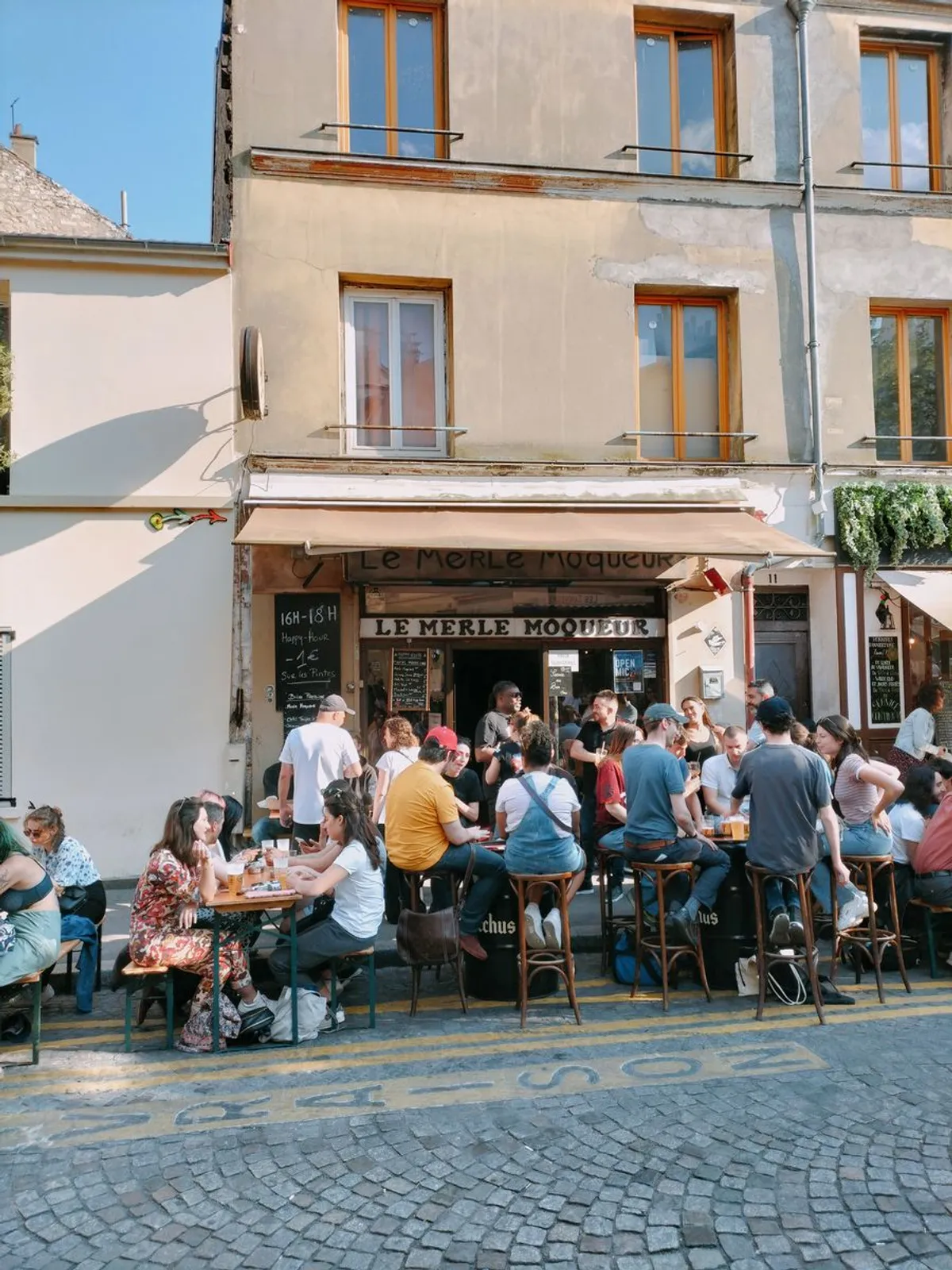 Façade du bar Le Merle Moqueur, terrasse ensoleillée rue de la Butte aux Cailles
